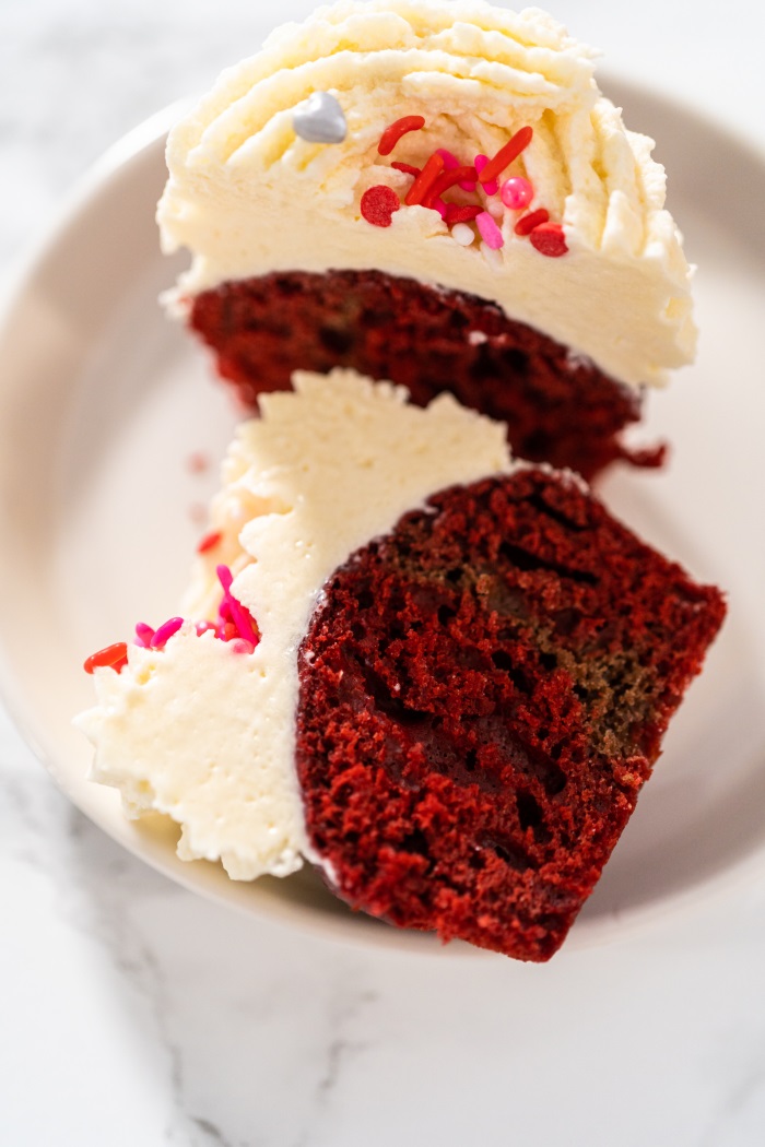 red velvet cupcake cut in half on a plate