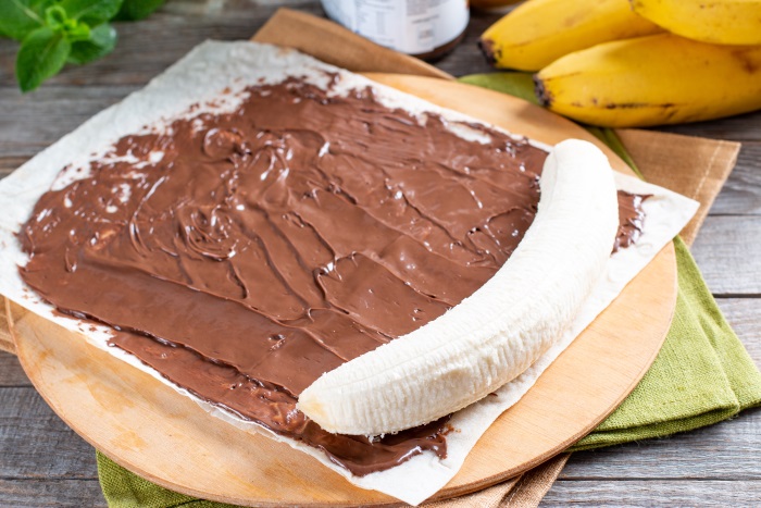 banana ready to be rolled inside crepe smeared with chocolate