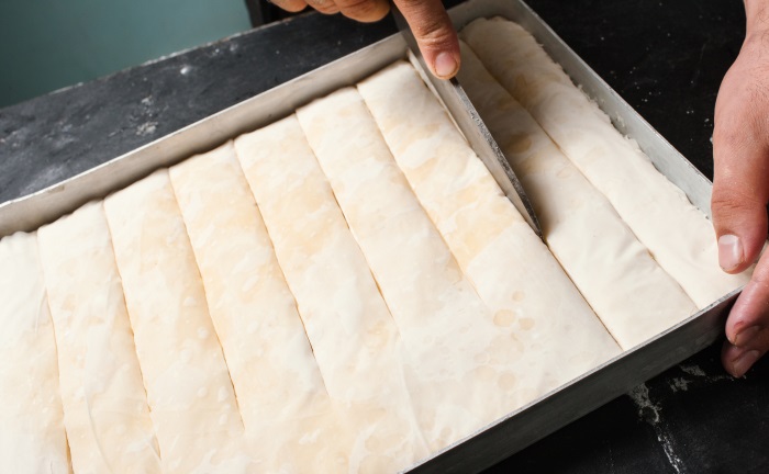galaktoboureko filo sheets in tray cut before baking